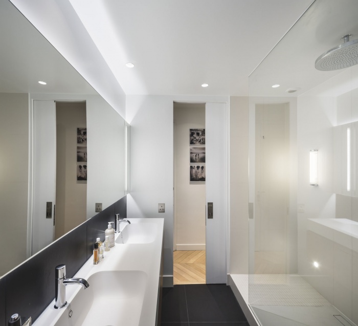Boulainvillers : Transformation d’une cuisine en salle de douche. Salle de douche profitant de la lumière naturelle et jouant sur le contraste noir et blanc. Elle est composée d’une porte d’accès à galandage, d’une douche avec double accès et d’une double vasque.